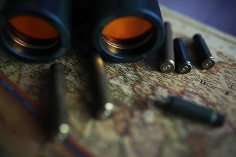 Binoculars and reflection in lenses. Map and shells background. Foto stock