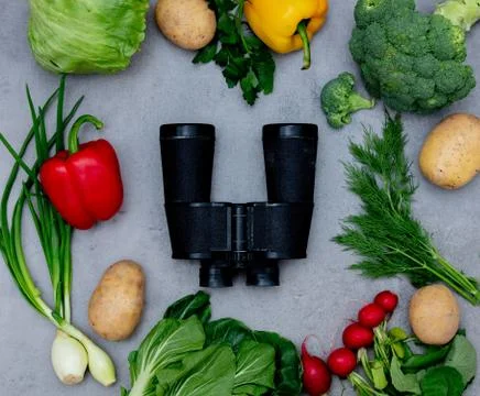 Binoculars and vegetables on a table. Stock Photos