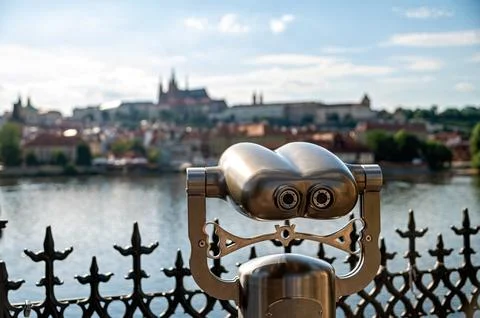 Binoculars are set up at a viewpoint over the Vltava River and Prague Castle. Photos