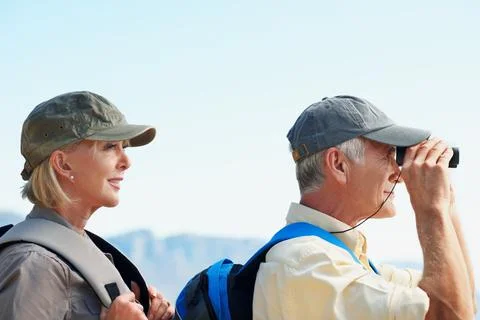 Binoculars, hiking and explore with old couple in nature for view, adventure and Foto stock