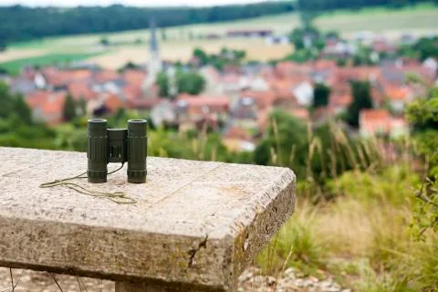 Binoculars on stone bench with view of a small town Foto stock