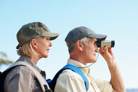 Binoculars, trekking and explore with old couple in nature for view, adventure Foto stock