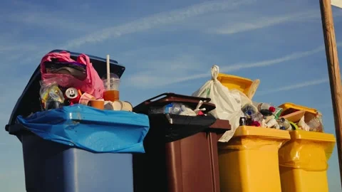 Bins filled with plastic and organic waste on a beach with the sea in the Video stock 334944007