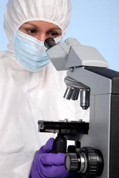 Biochemist looking through a microscope Stock Photos
