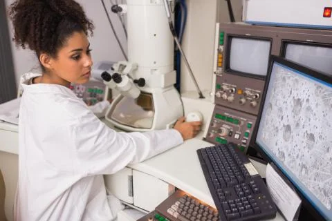 Biochemistry student using large microscope and computer 스톡 사진