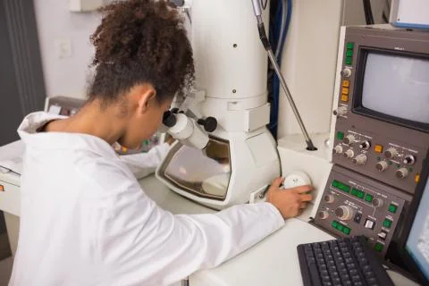 Biochemistry student using large microscope and computer 스톡 사진