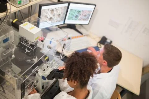 Biochemistry students using large microscope and computer 스톡 사진