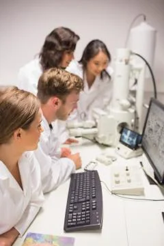 Biochemistry students using large microscope and computer Stockfoto's