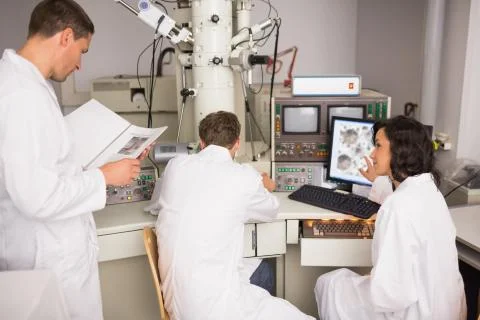 Biochemistry students using large microscope and computer 스톡 사진