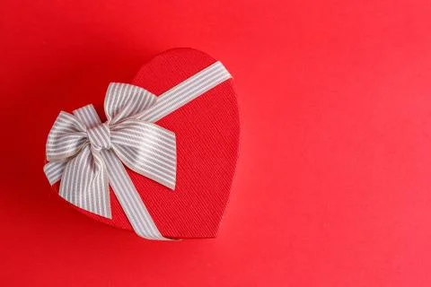 Biodegradable cardboard gift box in the shape of a heart with ribbons on red  Stock Photos