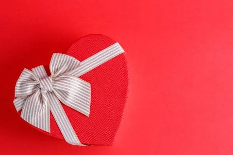 Biodegradable cardboard gift box in the shape of a heart with ribbons on red  Stock Photos