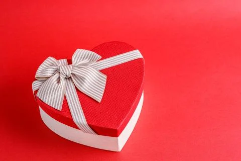 Biodegradable cardboard gift box in the shape of a heart with ribbons on red  Stock Photos