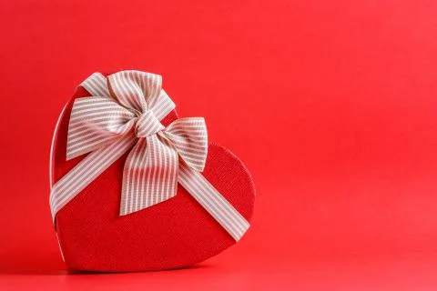 Biodegradable cardboard gift box in the shape of a heart with ribbons on red  Stock Photos