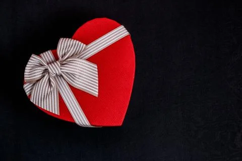 Biodegradable cardboard gift box in the shape of a heart with ribbons on blac Stock Photos