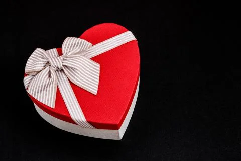 Biodegradable cardboard gift box in the shape of a heart with ribbons on blac Stock Photos