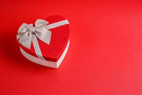 Biodegradable cardboard gift box in the shape of a heart with ribbons on red  Stock Photos
