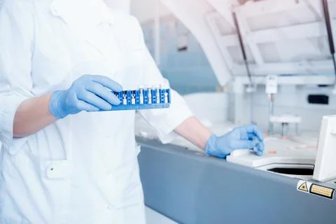 Bioengineer installs blood plasma sample in automatic tester for DNA analysis Stock Photos