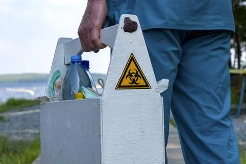 Biohazard sign on the box with samples of water from the lake in the hands .. Stock Photos