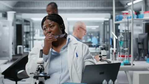 Bioinformatics scientist doing brainstorming while working on laptop in lab Stock Footage 325819562
