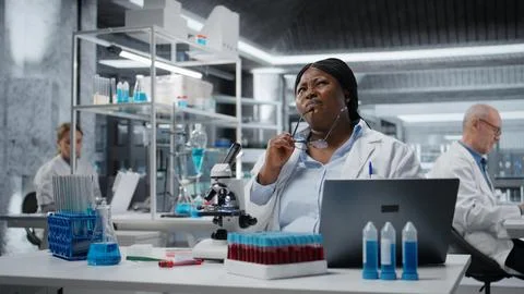 Bioinformatics scientist doing brainstorming while working on laptop in lab Stock Photos