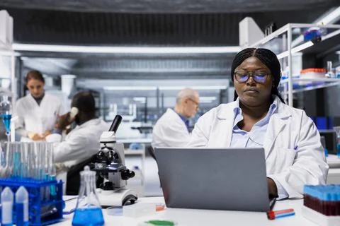 Bioinformatics scientist in lab documents clinical trial outcomes on laptop Fotos Stock