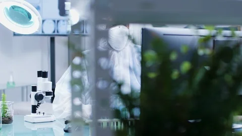 Biologist dressed in protective coverall and wearing a mask is lookign at a Stock Footage 113671970