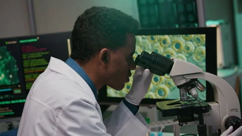Biologist Evaluating Mutation of Cells Using Microscope and Computers in Lab Stock Footage 332362550