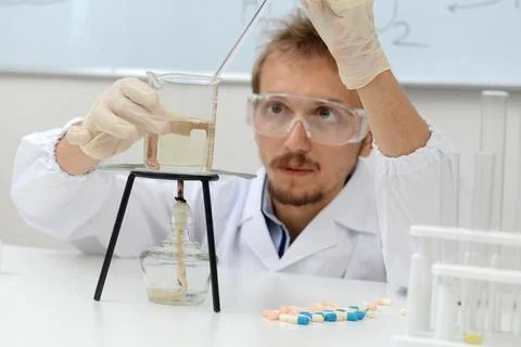 Biologist examines analysis data from a heated chemical flask Stock Photos