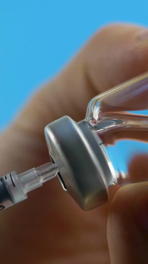 Biomedical scientist hand draws medication from vial into syringe Stockbeeldmateriaal 317518854