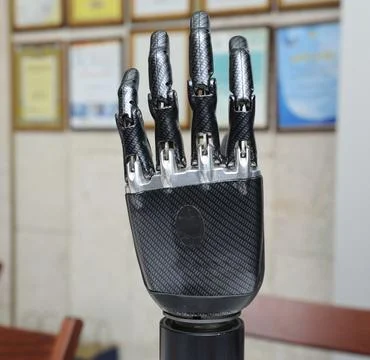 Bionic prosthetic hand close up against blurred framed certificates on the wa Stock Photos