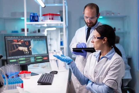 Biotechnology scientists teamworking at computer researching in development Stock Photos