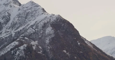Biplane coming into frame in front of mountain, drone, helicopter aerial Stock Footage 107789064