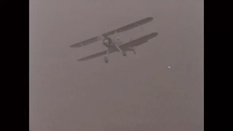 Biplane flying over the landscape during pilot training - 1940 Stock Footage 100285398