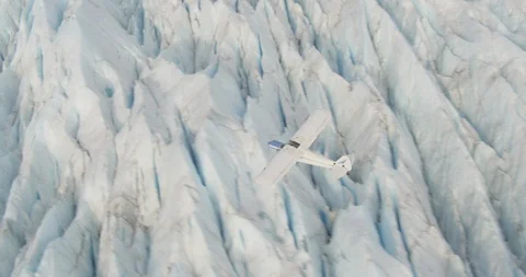 Biplane flying over sharp icy landscape, drone aerial Stock Footage 107856829