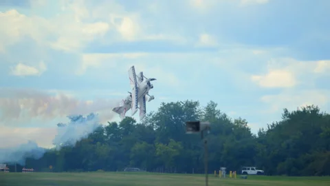 Biplane performing a steep vertical climb maneuver at airshow, leaving a smoke Stock Footage 318049779