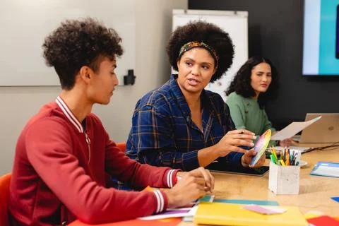 Biracial app developers discussing over color swatch during meeting in board Foto stock