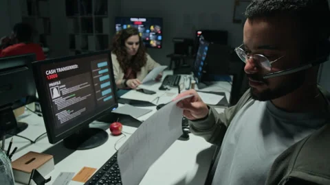 Biracial Man Wearing Headset Checking Scam Documents in Call Center Stock Footage 346704471