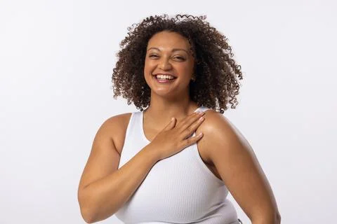 A biracial plus size model with curly brown hair laughs on white background, Stock Photos