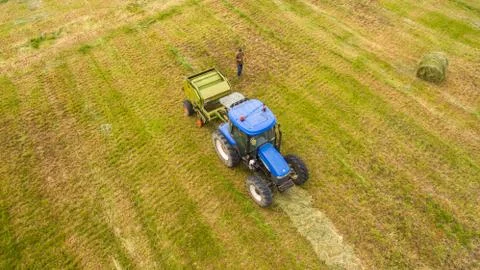 Bird eye of Man at work on the tractor with hay baler Stock Photos