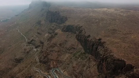 Bird eye view of camera flying between high rocks with the lonely winding road Stock Footage 94119637