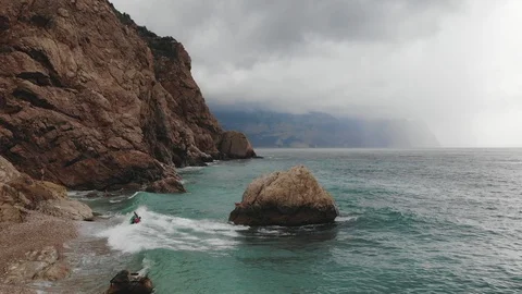 Bird eye view sea waves roll on cliffs under sky with clouds Video stock 103182504