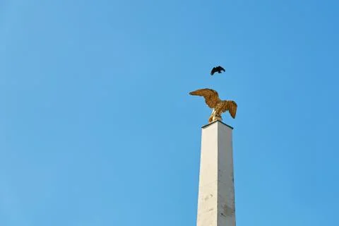 Bird flies over a gilded eagle on a column at main gate of the Schonbrunn palace Stock Photos