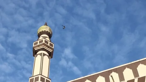 A bird flies on top of a mosque against a beautiful blue sky background Stock Footage