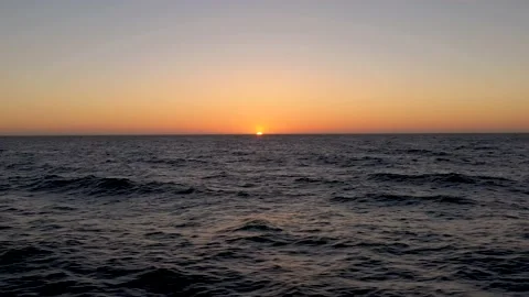Bird flying across the frame while the sun sets below the horizon in the ocean. Stock-Footage 218350768