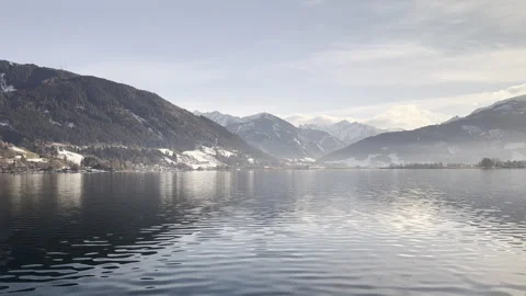 A bird flying over snow-capped mountains and reflective winter water Stock Footage 300119231