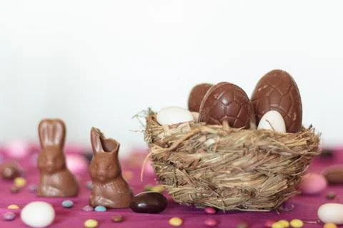 Bird nest with chocolate easter eggs and chocolate bunny on table Stock Photos