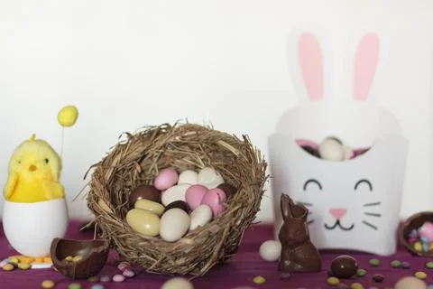 Bird nest with easter almond eggs, chocolate bunny missing a bite, treat box  Stock Photos