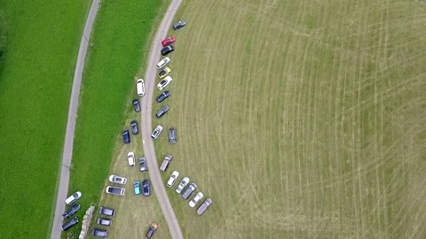 Bird perspective directly down on a field with parked cars. A car pulls Video stock 122928580