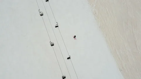Bird view of a solo skier going down a ski slope under a ski lift Stock Footage 172728119