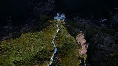 Birds eye aerial view over a waterfall in Iceland, flowing into the ocean. Video stock 166314743